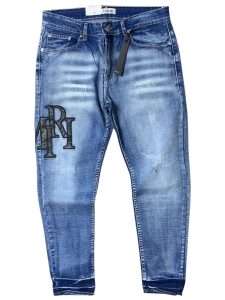 AMIRI em lavagem azul clara com detalhes desgastados e aplicação de patch com o logotipo em destaque na perna.